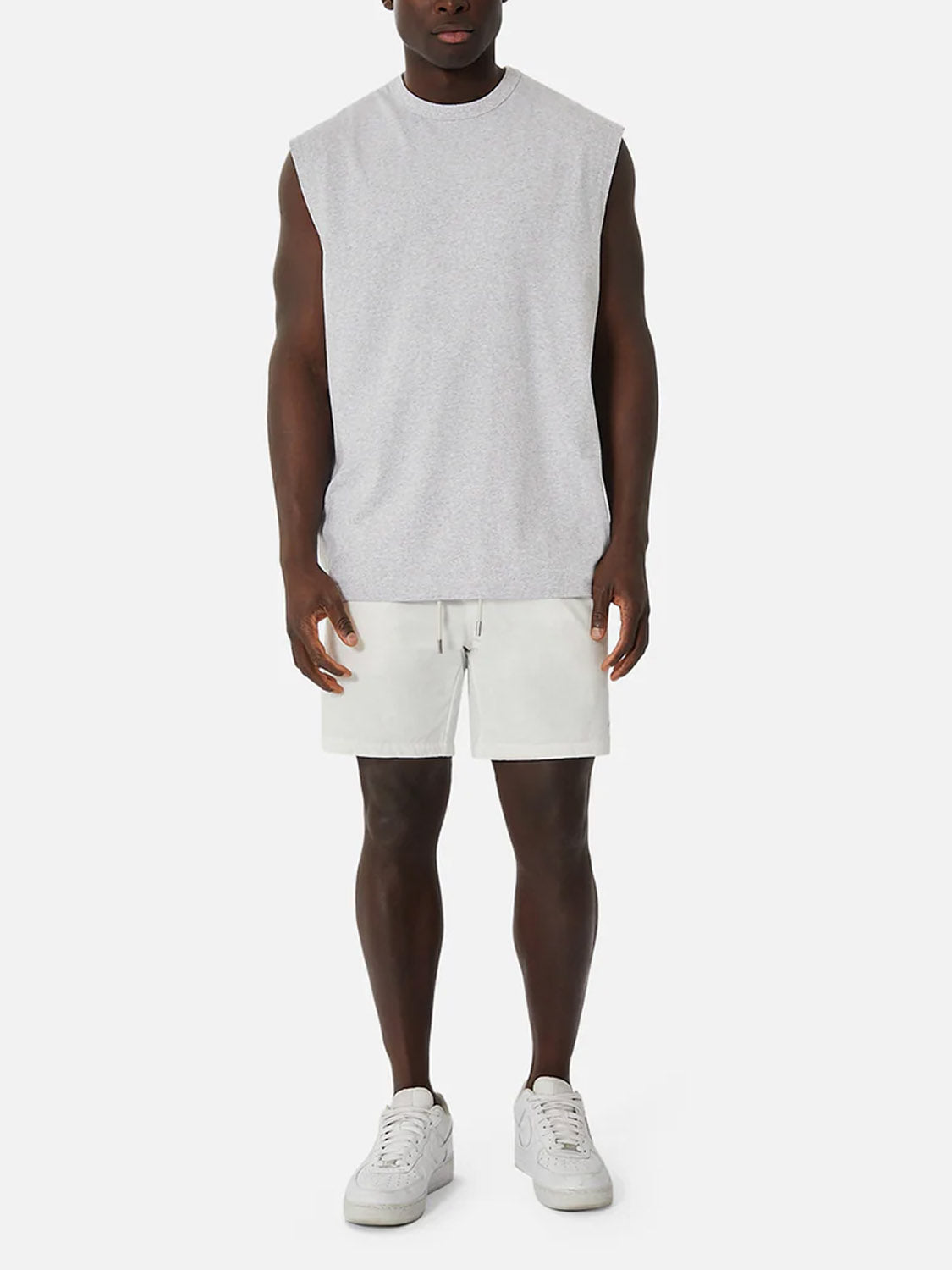 A person faces forward wearing the Industrie Del Sur Sleeveless T-Shirt, paired with light gray shorts and white sneakers, set against a plain white background.