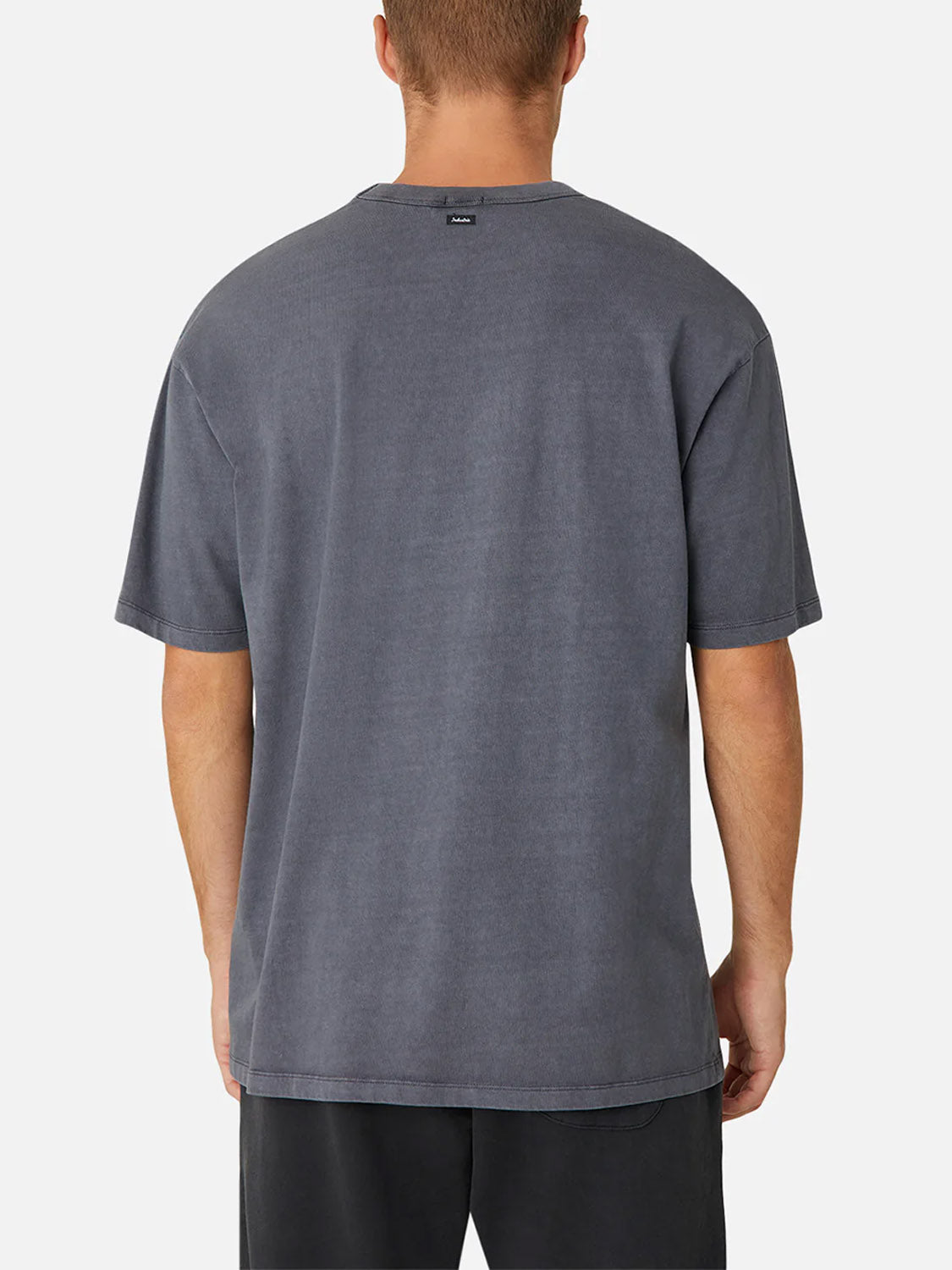 A man is seen from the back wearing Industrie’s The Del Sur Tee, a relaxed fit, short-sleeve, faded gray 100% cotton crew neck t-shirt, paired with black shorts against a plain white background.