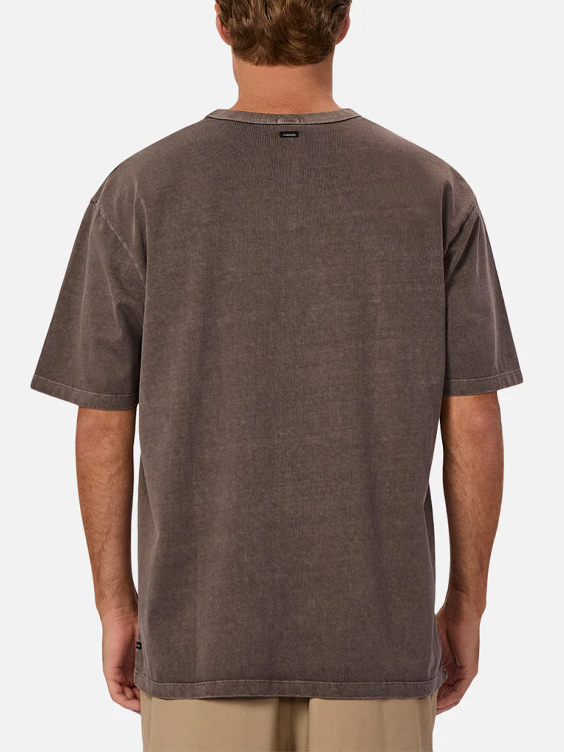 A person wearing The Del Sur Tee by Industrie—a relaxed fit, short-sleeve brown crew neck t-shirt—with beige pants, shown from the back against a plain white background.