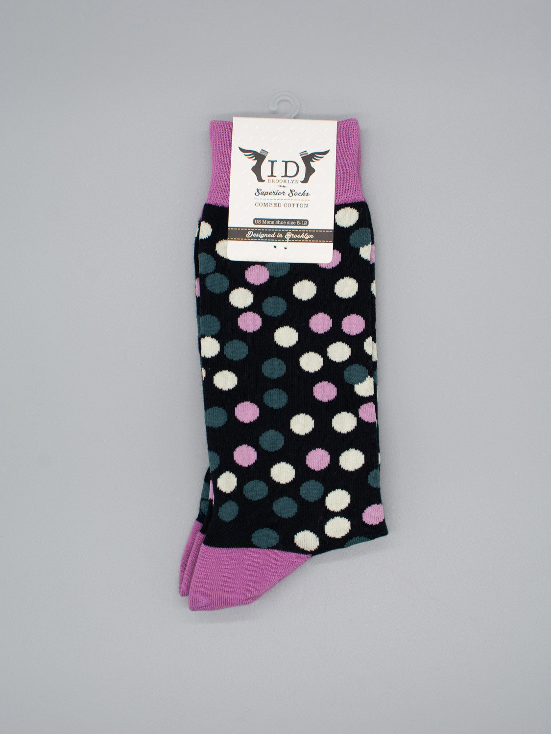 The Disco Graphic Socks by ID Menswear are black with white, pink, and gray polka dots and feature purple cuffs, heels, and toes. Made from high-quality combed cotton, they include a branded white label at the top.