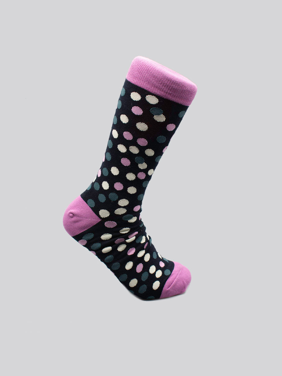 The Disco Graphic Sock by ID Menswear, crafted from premium combed cotton, features black fabric with white, light blue, and pink polka dots plus a pink toe, heel, and cuff—shown against a plain light gray background.