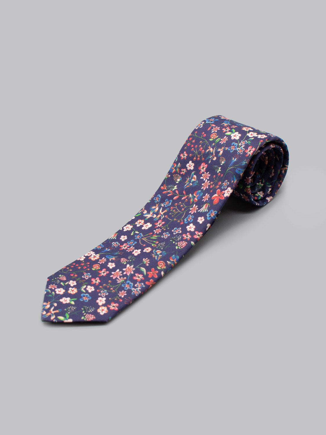 The Liberty of London Tana Lawn™ Donna Tie by ID Menswear is handmade in Brooklyn from soft cotton, featuring a colorful floral print on a light gray background with navy accents.