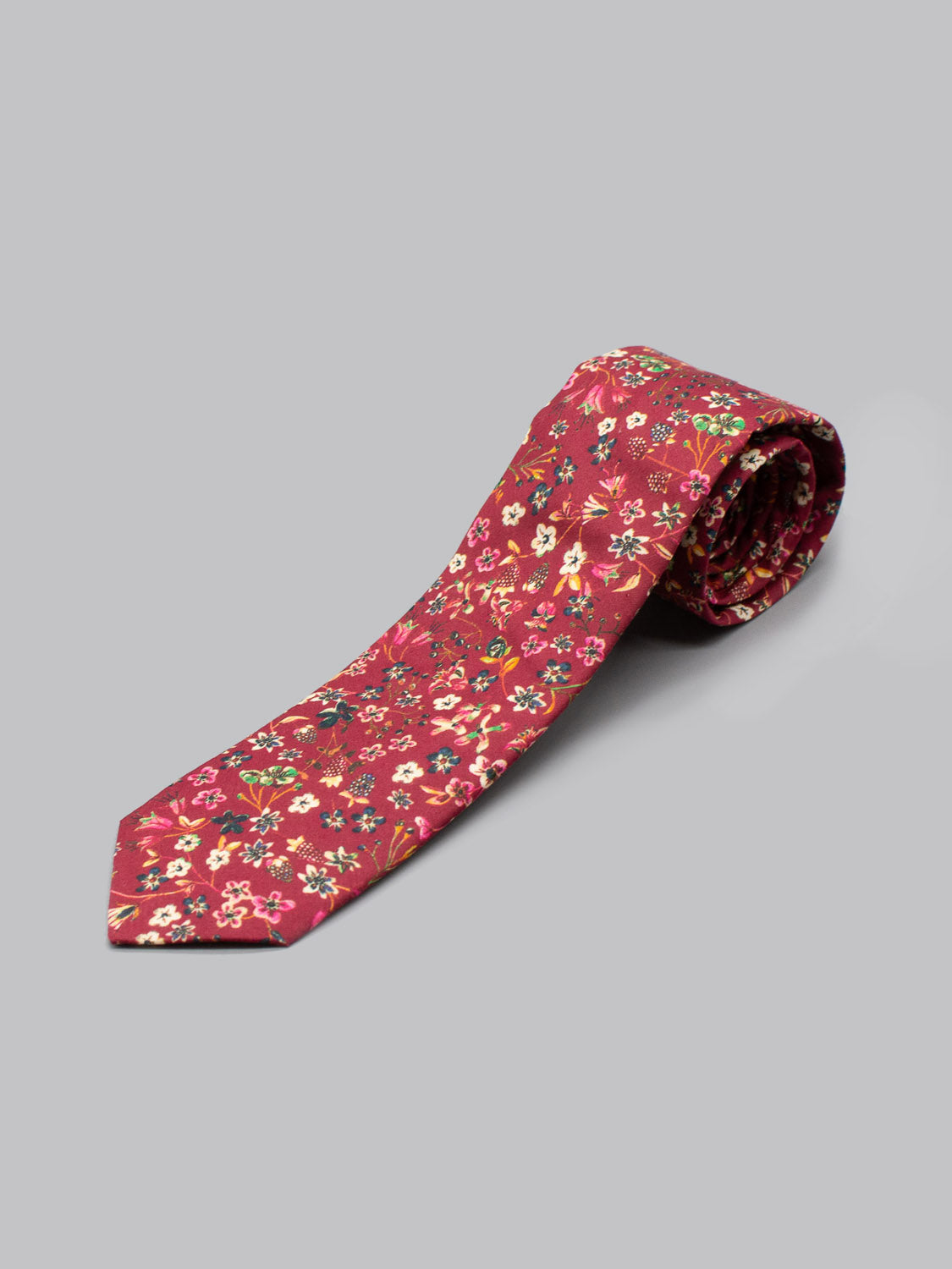 The Liberty of London Tana Lawn™ Donna Tie by ID Menswear is a handmade red floral tie with white, pink, and yellow blooms, crafted in Brooklyn from luxurious Tana Lawn cotton and shown on a plain light gray background.