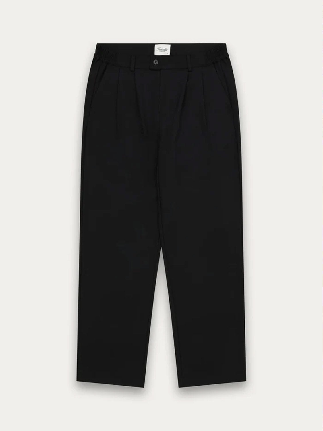 The Kuwalla Double Pleated Pants are black tailored trousers with double pleats, button and zip closure, side pockets, and a white waistband label, shown against a plain light background.