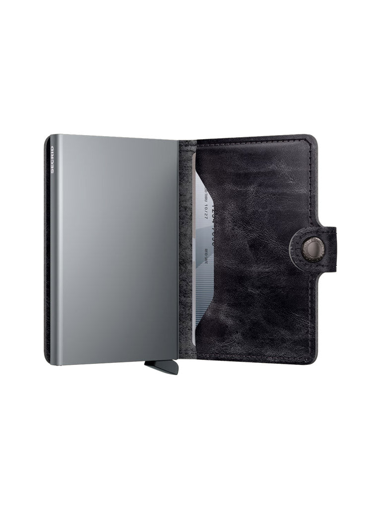 A black leather Secrid Miniwallet Dutch Martin with RFID protection and snap button, featuring a metallic card holder on the left and a partially visible card on the right, is displayed on a white background.