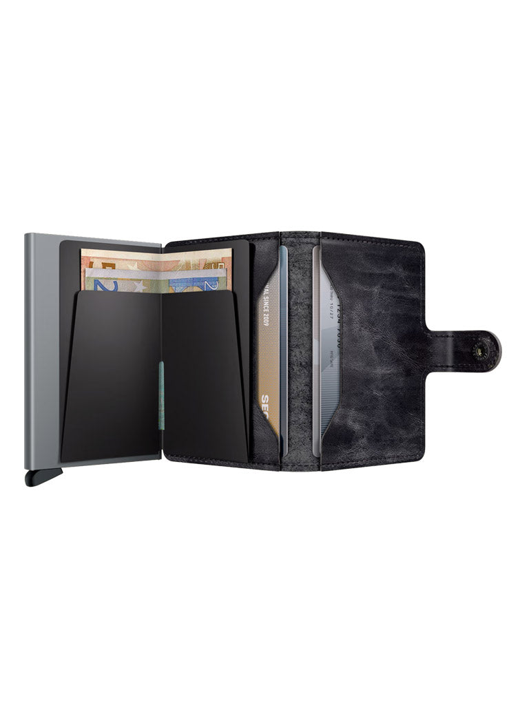 The Secrid Miniwallet Dutch Martin, a black leather RFID wallet with snap closure, is open to reveal euro banknotes and several credit cards organized in slots—showcasing Secrid’s perfect blend of style and security.