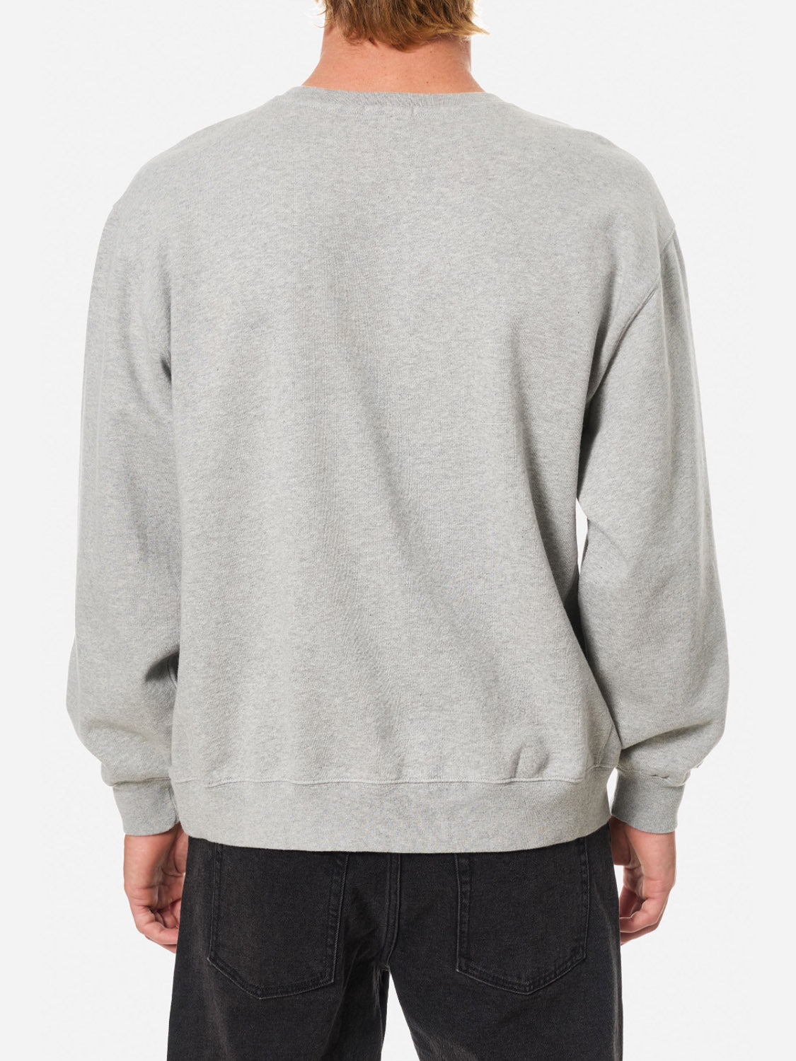 A person with light brown hair is shown from the back, wearing the Katin Embroidered Crewneck sweatshirt in light grey fleece and black jeans, set against a white background.