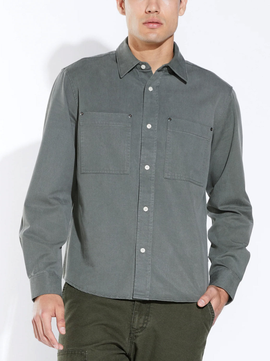 A person wears the Civil Society Ernst Relaxed Fit Long Sleeve Shirt, a button-up cotton blend twill overshirt with two chest pockets, standing against a plain light background with their head partially out of frame for a classic workwear vibe.