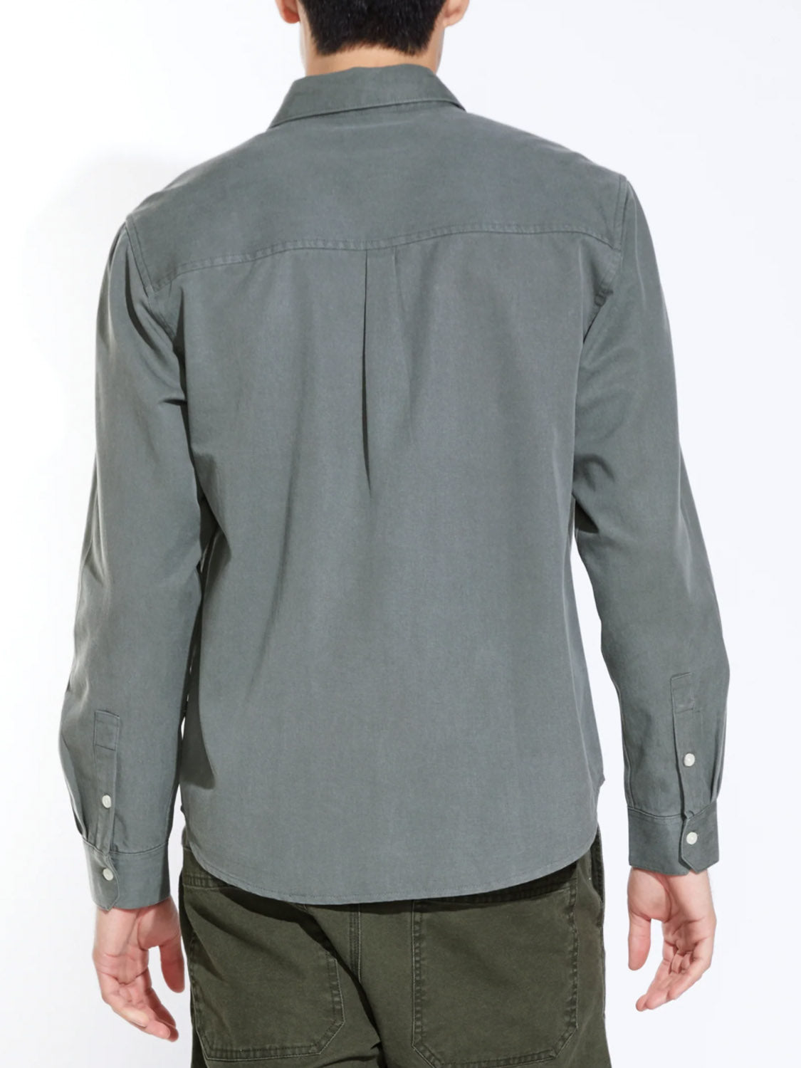 A person is seen from behind wearing the Civil Society Ernst Relaxed Fit Long Sleeve Shirt in sage green, paired with matching green pants, evoking classic American workwear against a plain white background.