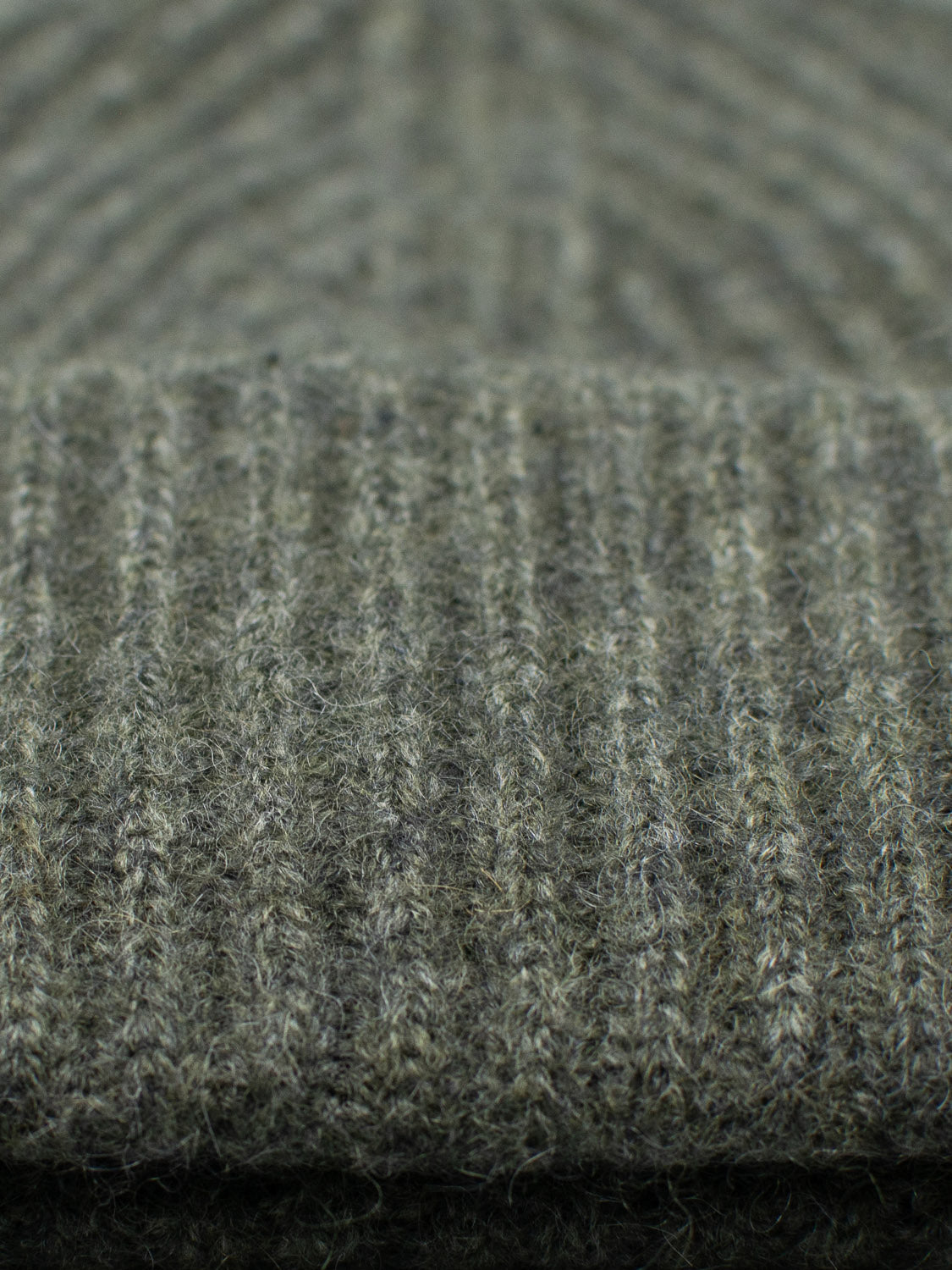 Close-up of the Everest Cashmere Beanie by ID Menswear in muted green, showcasing its soft, fuzzy cashmere fibers and vertical ribbed knit—an ideal lightweight accessory to complement any versatile style.