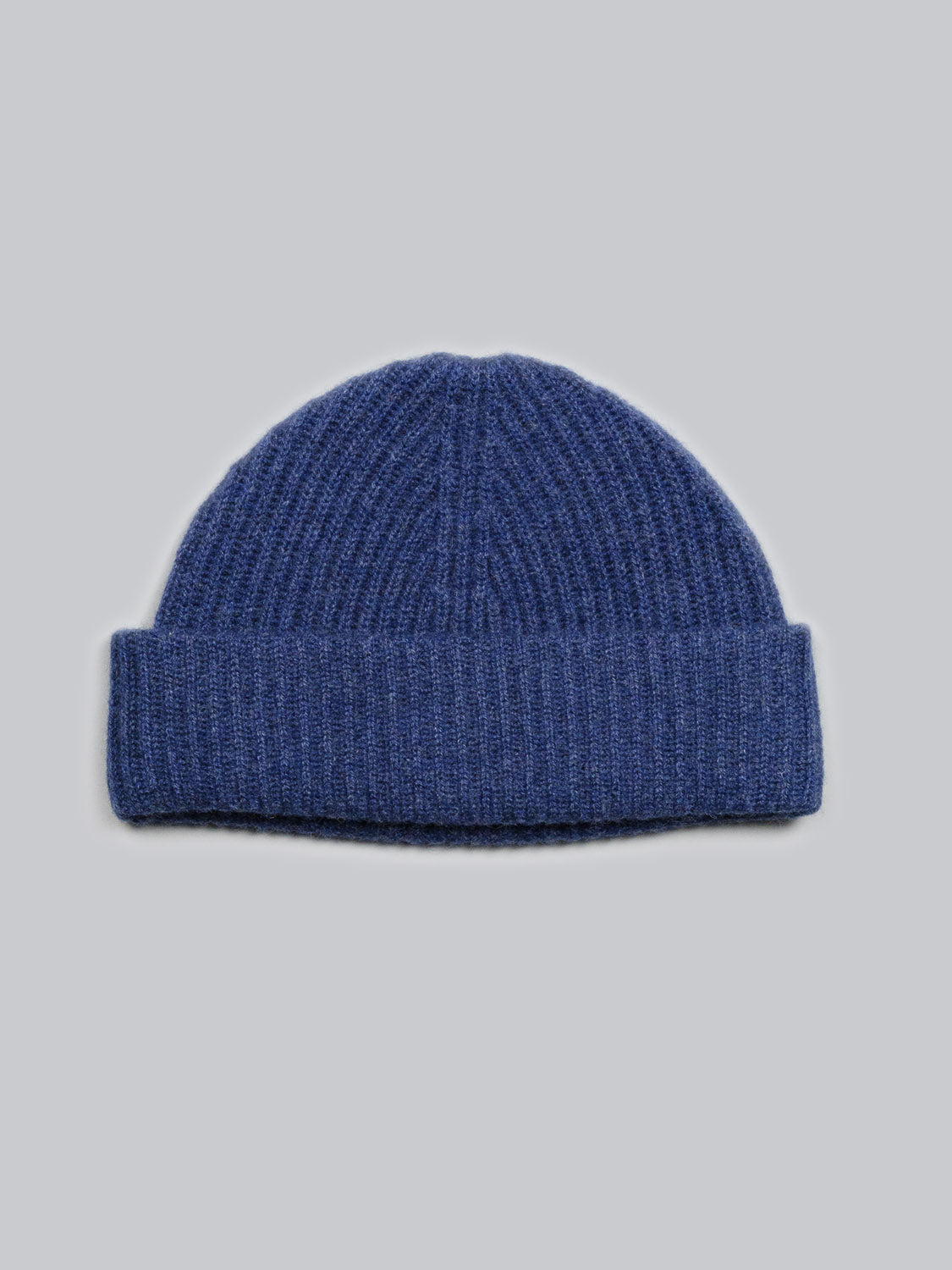 The Everest Cashmere Beanie by ID Menswear is a blue ribbed knit hat with a folded brim, shown on a light gray background. This lightweight accessory provides versatile style for any season.
