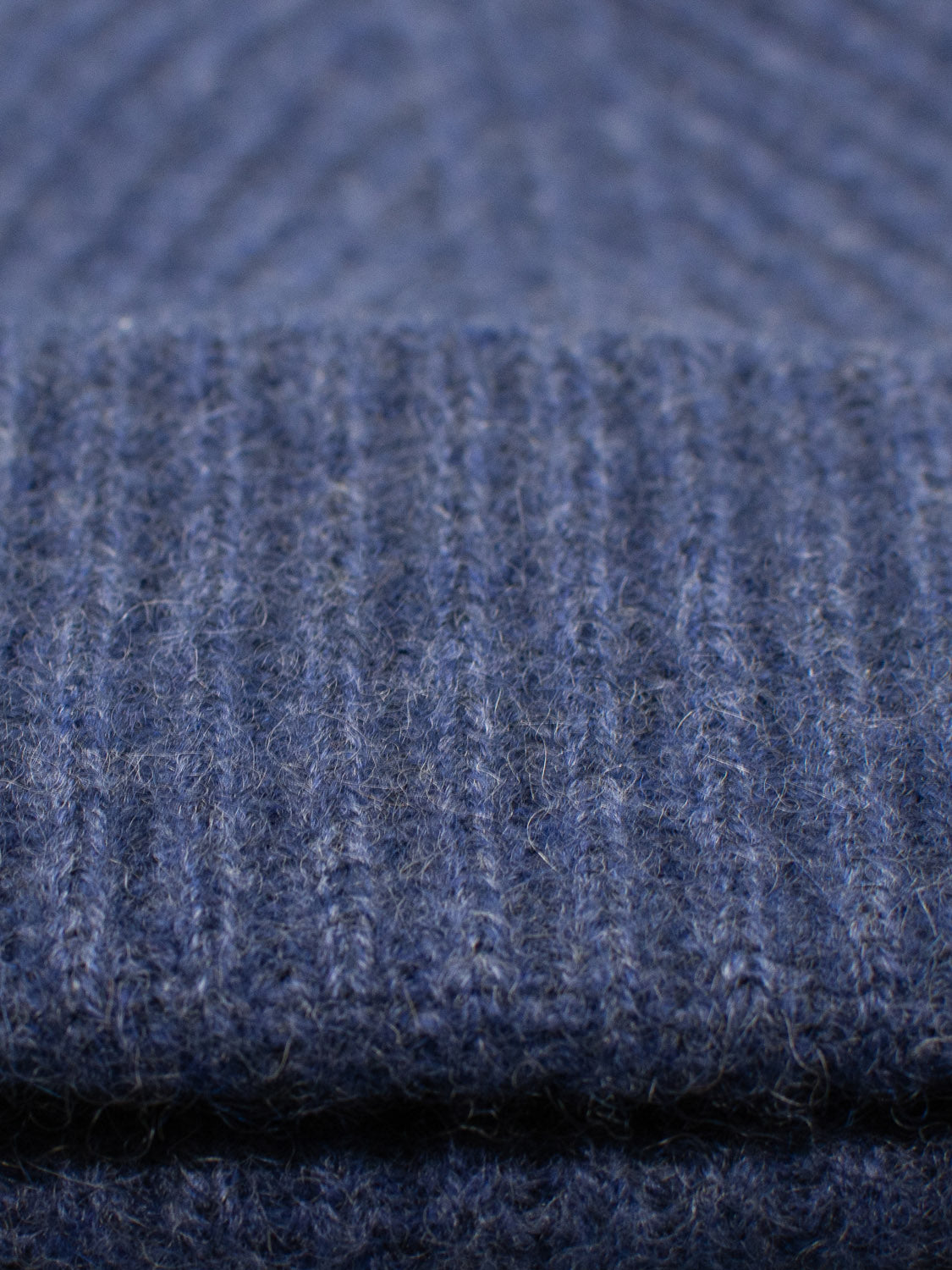 Close-up of the Everest Cashmere Beanie by ID Menswear, featuring blue ribbed knit and soft, fuzzy cashmere fibers. The image emphasizes the lightweight texture and detailed pattern of this stylish accessory.