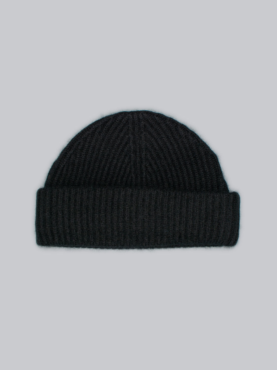 The Everest Cashmere Beanie by ID Menswear is a black, ribbed knit hat with a folded brim, shown on a gray background. Lightweight and stylish, it’s a versatile accessory for any wardrobe.