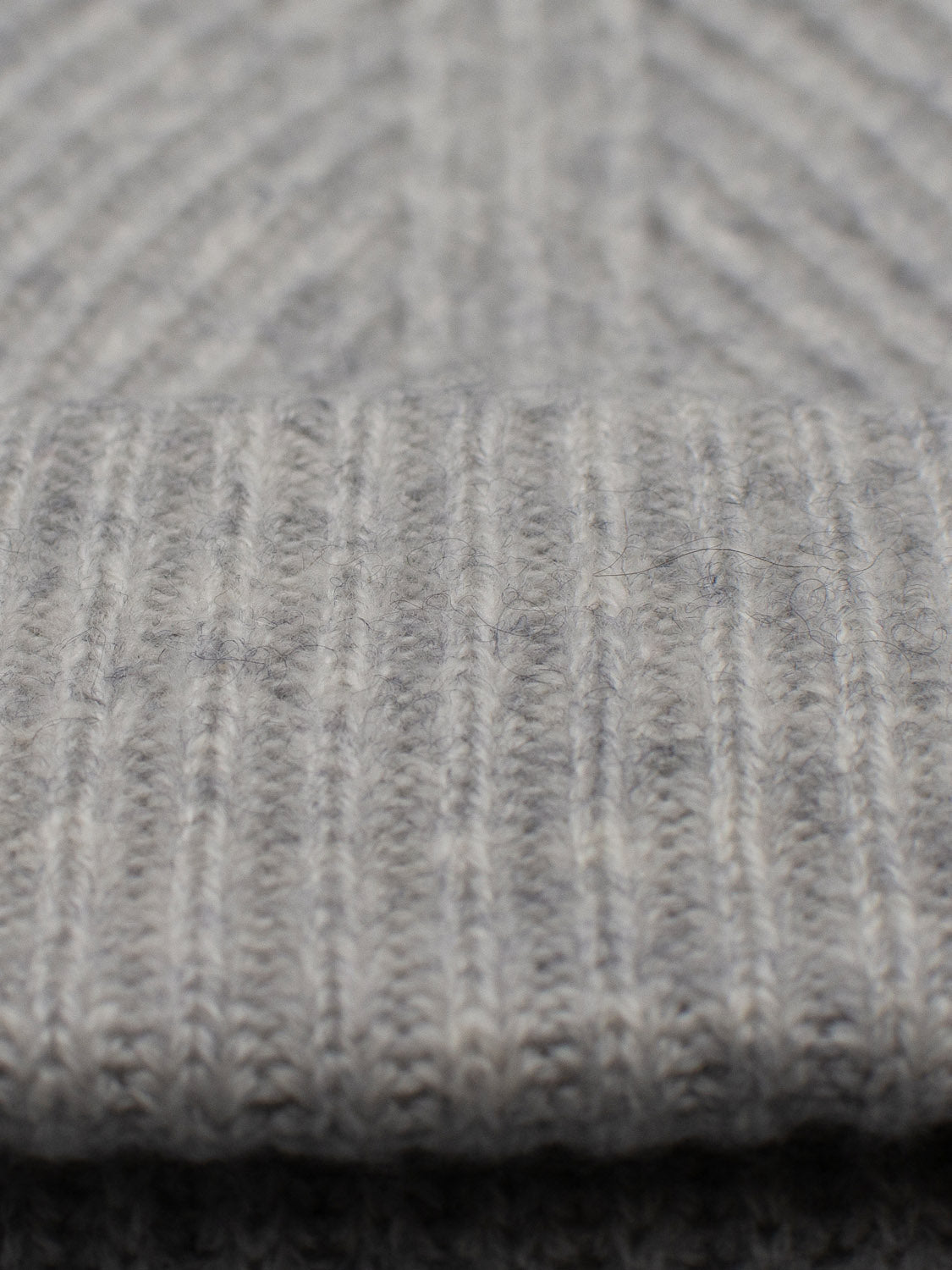 Close-up of the Everest Cashmere Beanie by ID Menswear, featuring soft, light gray ribbed knit fabric that highlights the fine yarn and stitching—a lightweight, versatile accessory for any style.