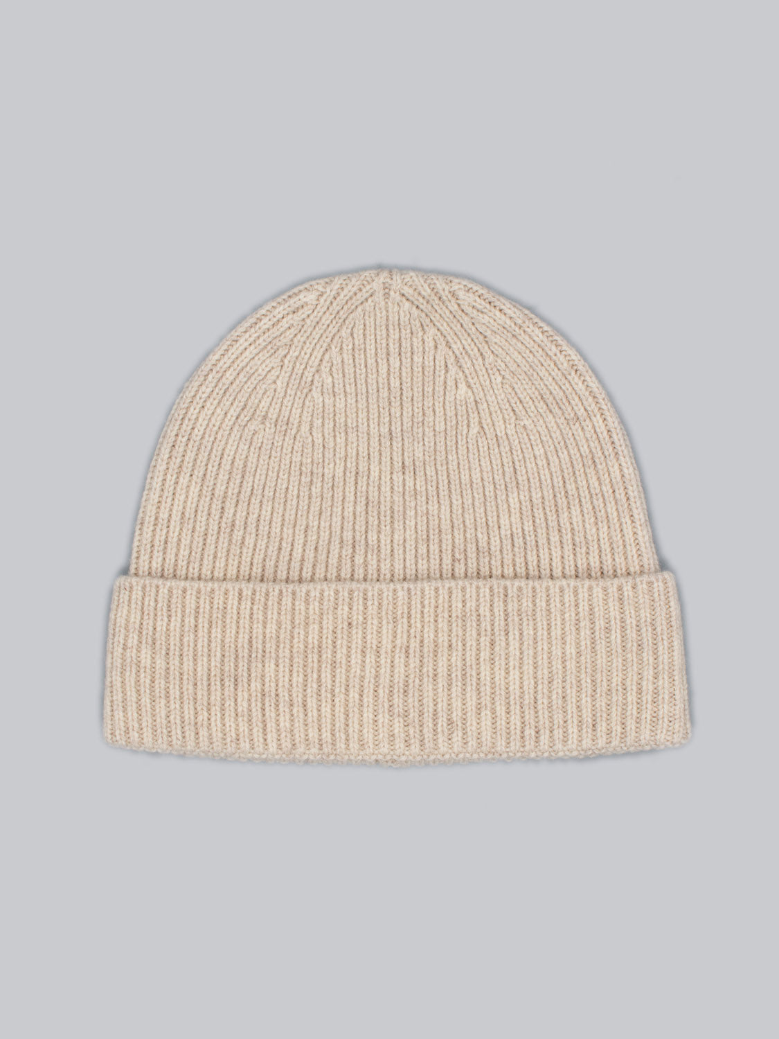 The Fuji Merino Wool Beanie by ID Menswear, in beige with a folded cuff, made from 100% Merino Wool, is stylishly showcased on a light gray background—your ideal winter accessory.