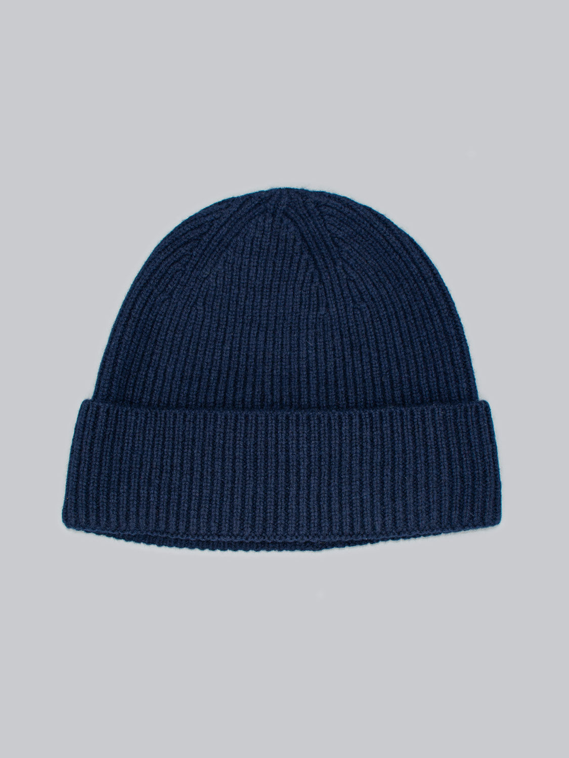 The Fuji Merino Wool Beanie by ID Menswear, in dark blue with a ribbed texture and wide folded cuff for winter warmth, is displayed on a plain light gray background.