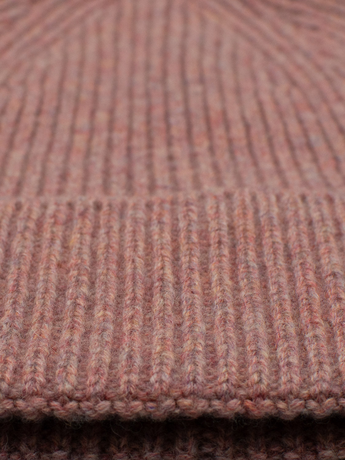 Close-up of the Fuji Merino Wool Beanie by ID Menswear, featuring ribbed knitted fabric made from warm Merino wool in soft brown and pinkish hues, perfect for a cozy winter.