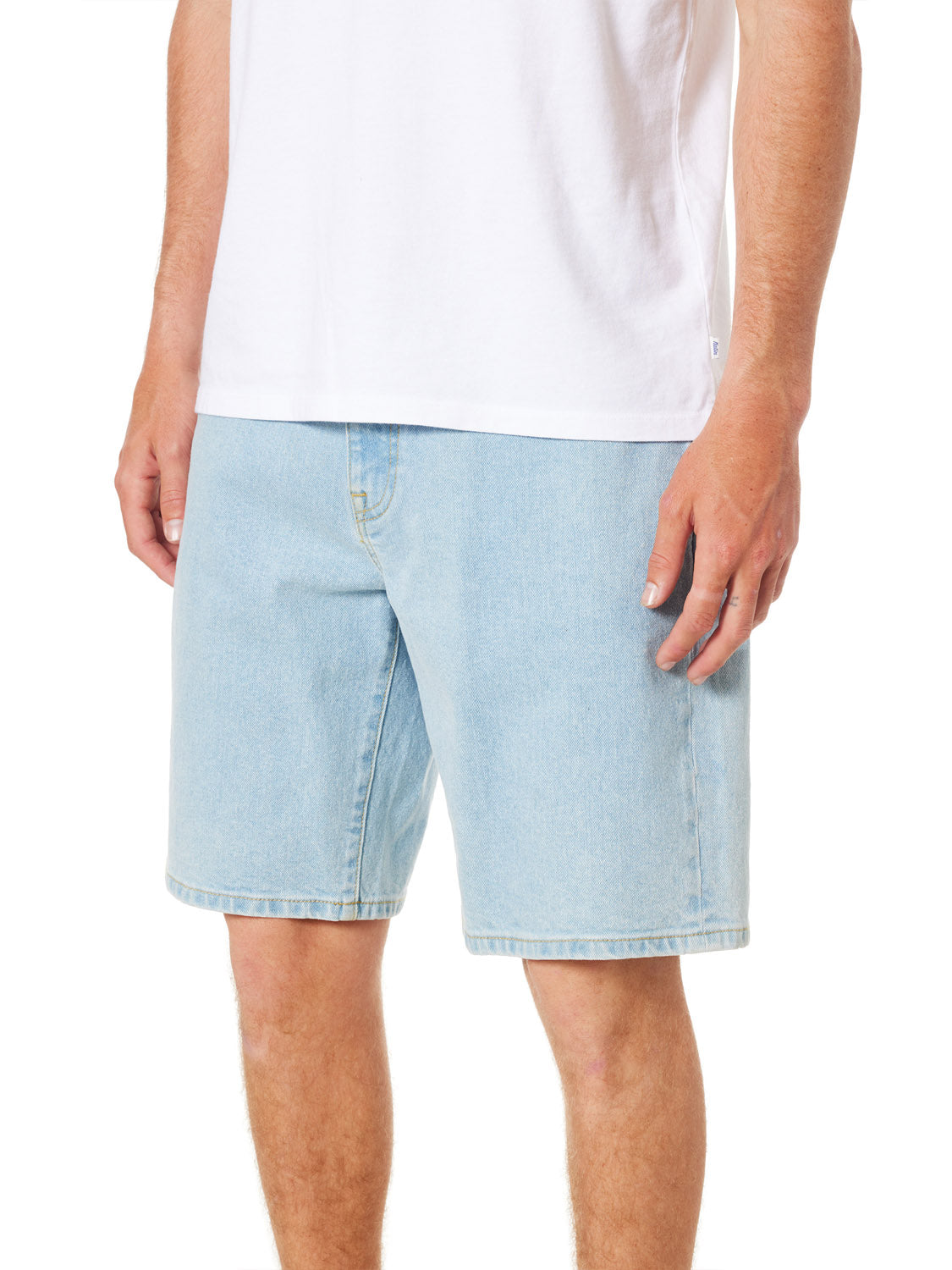 A person wearing a white t-shirt and light blue Katin George 64 Short - 20 in a relaxed fit stands against a plain background, revealing their lower half with one hand visible.