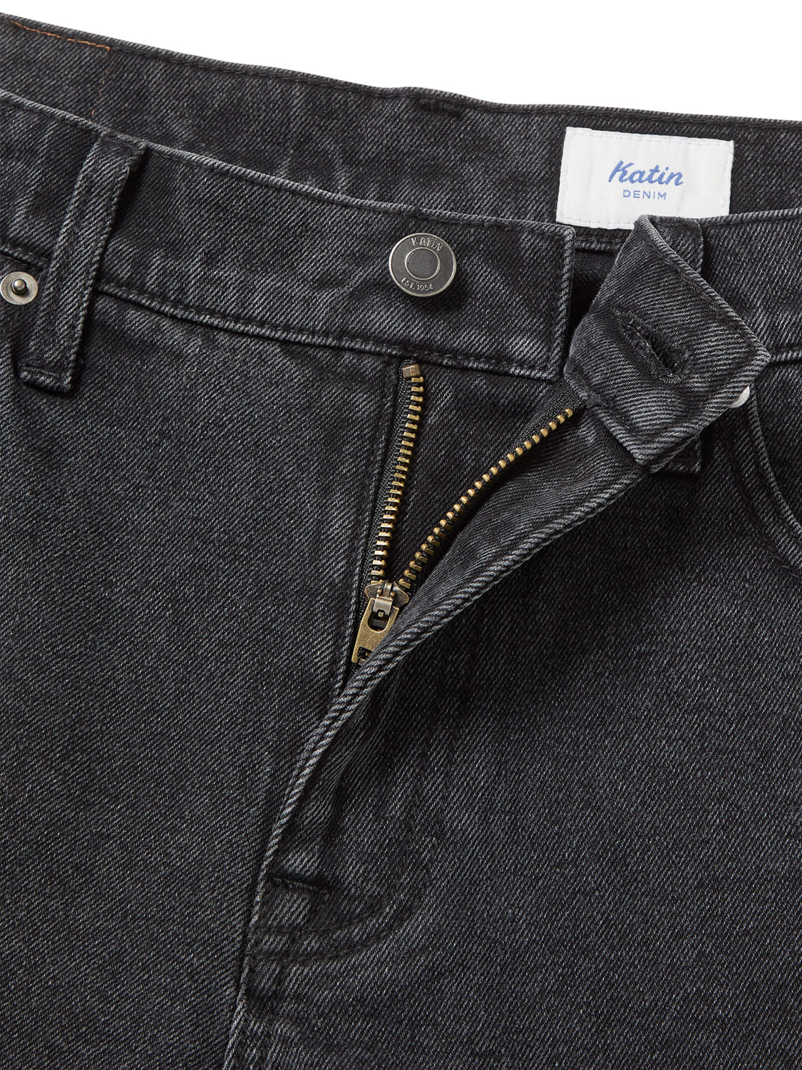Close-up of Katin denim shorts in a classic black wash, featuring a partially unzipped metal zipper and a button at the waist. The tag inside reads Katin George 64 Short - 20.