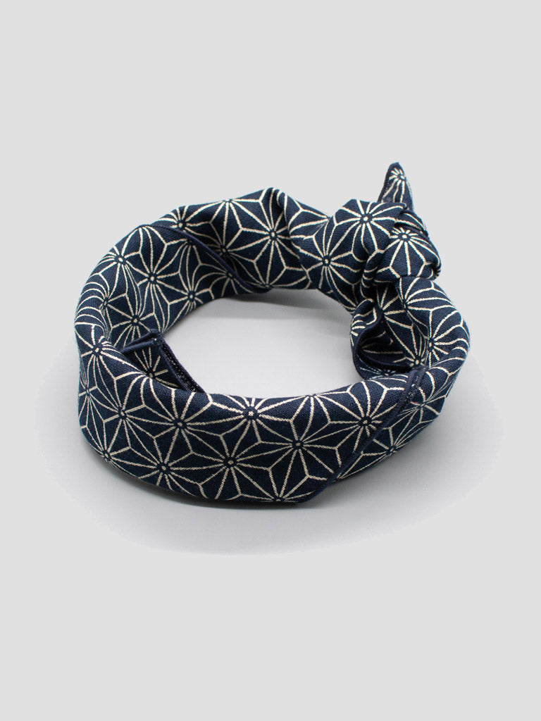 The ID Menswear Japanese Geometric Bandana bracelet features a navy blue and white Asanoha pattern, tied in a knot and shown on a light gray surface—ideal for fans of Japanese cotton bandana style.
