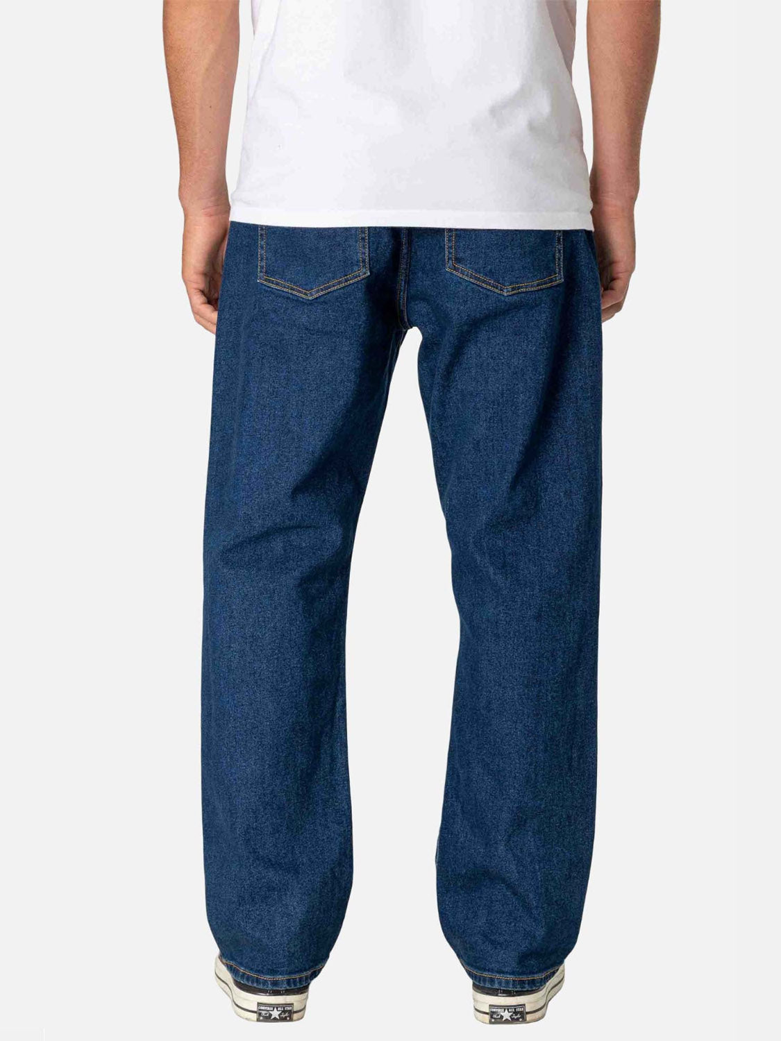 A person wearing Katin’s George 64 Relaxed Pants, a white T-shirt, and white sneakers with black details stands with their back to the camera against a plain white background.