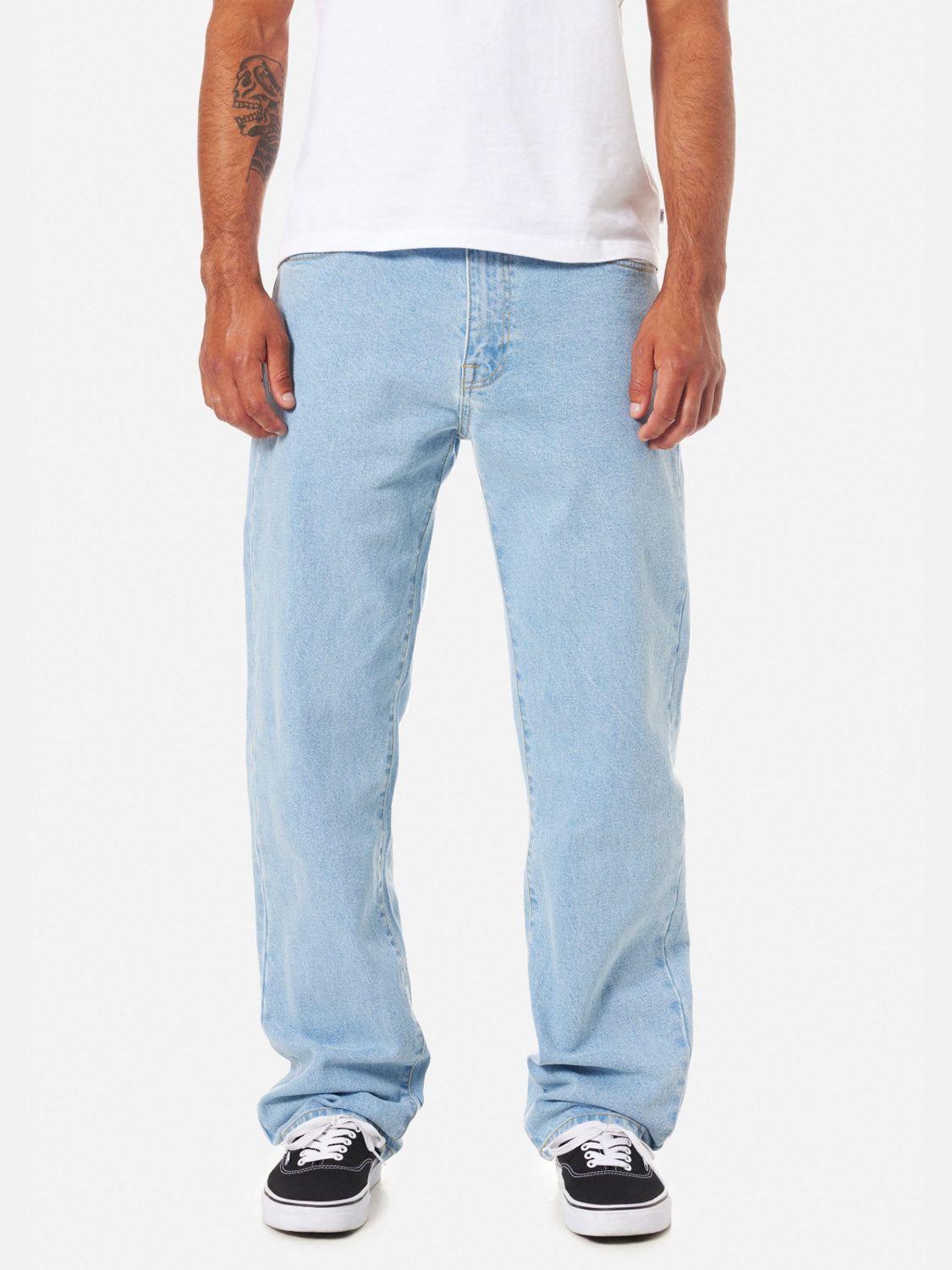 A person stands against a plain white background, showing only their lower half, wearing Katin George 64 Relaxed Pants, a white t-shirt, and black-and-white sneakers.