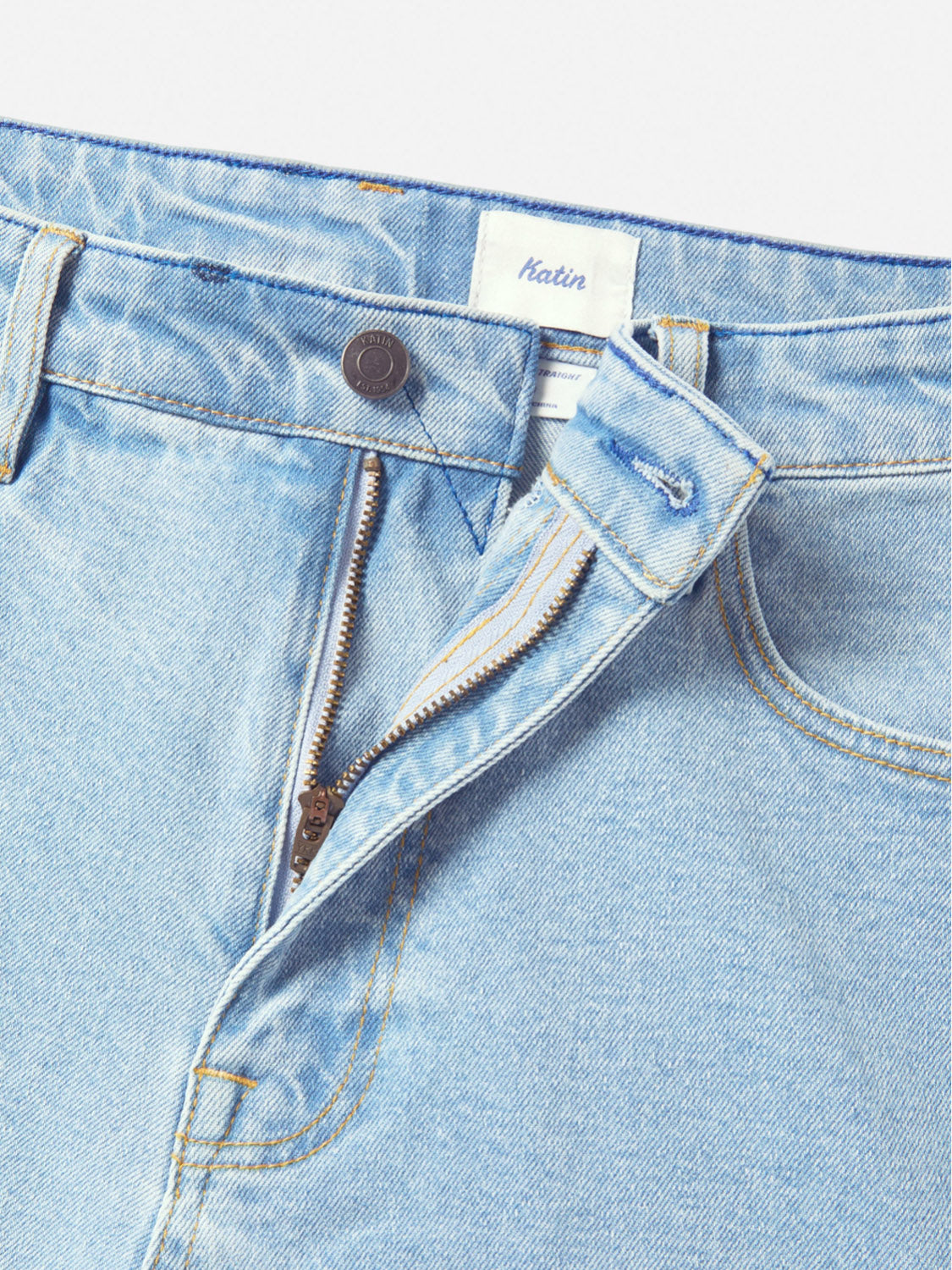 The Katin George 64 Relaxed Pants feature a light wash, straight fit, partially unzipped fly with a visible metal button, classic 5-pocket styling, and a white Katin label on the waistband.