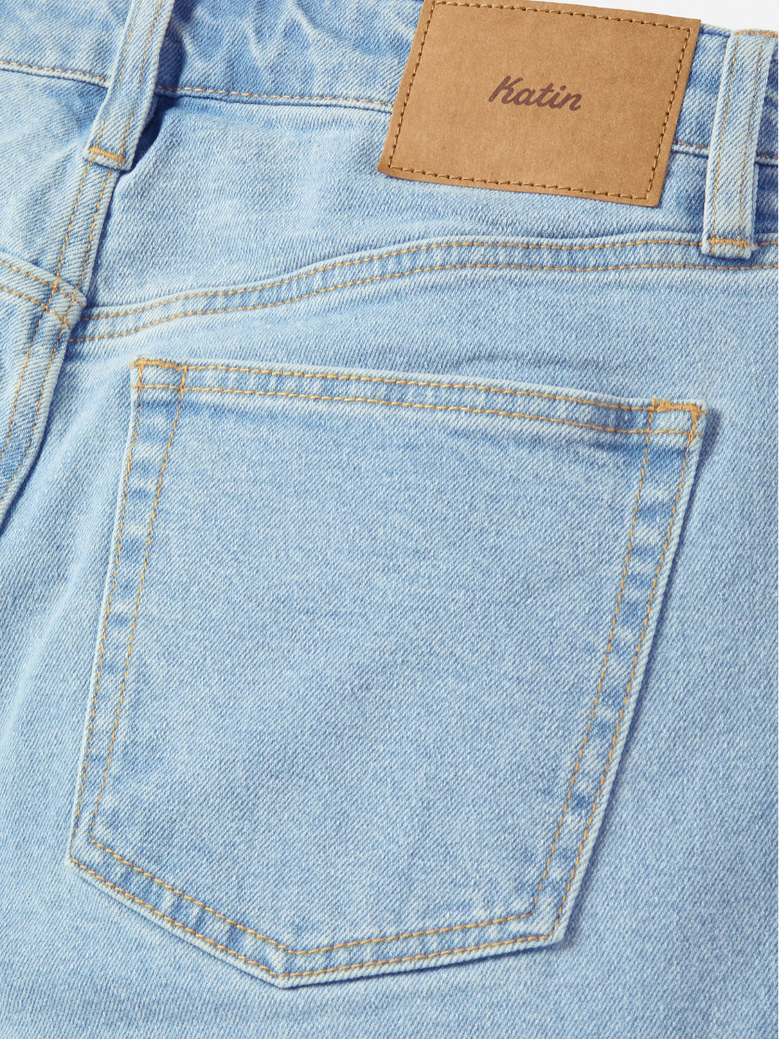 Close-up of the back pocket of the light blue Katin George 64 Relaxed Pants, featuring a brown leather patch above the pocket with the brand name embossed.