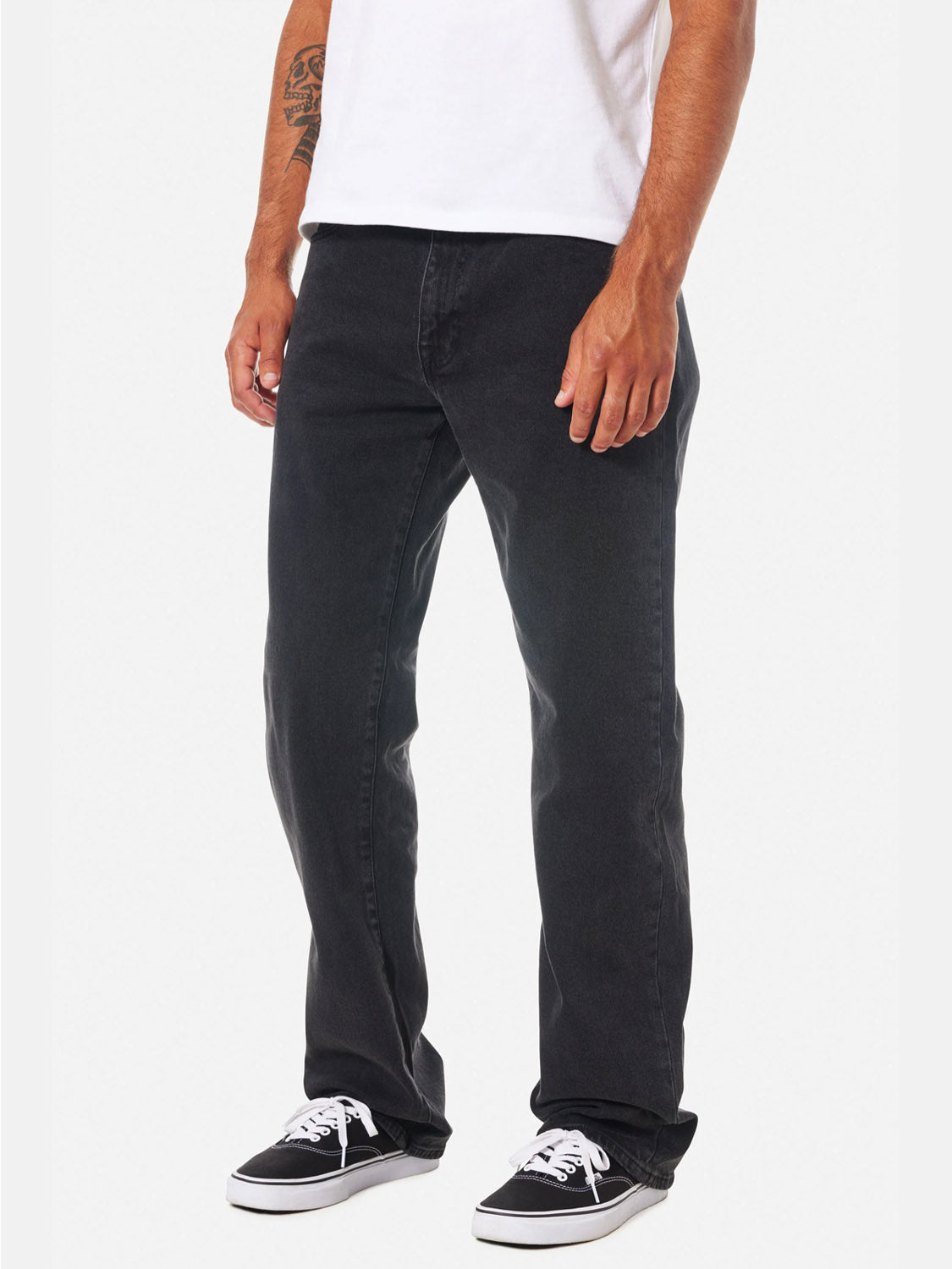 A person wearing a white t-shirt, Katin George 64 Relaxed Pants in black with 5-pocket styling, and black-and-white sneakers stands facing slightly left. Only the body from the shoulders down is shown.