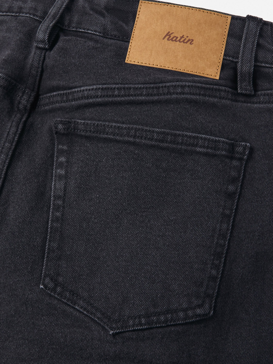 Close-up of the back pocket and waistband of George 64 Relaxed Pants by Katin, featuring a brown leather patch with the brand name in cursive above the pocket.