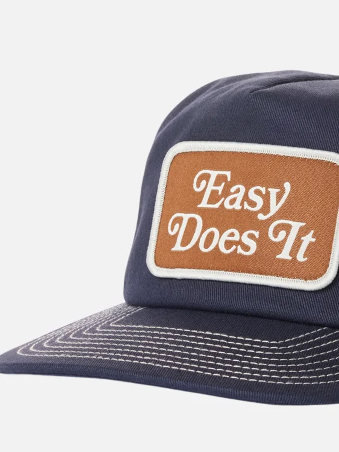 The Katin Good Times Trucker Hat is a navy cotton twill cap with white stitching, a brown front patch reading "Easy Does It" in white, and an adjustable snapback closure for a comfortable fit.