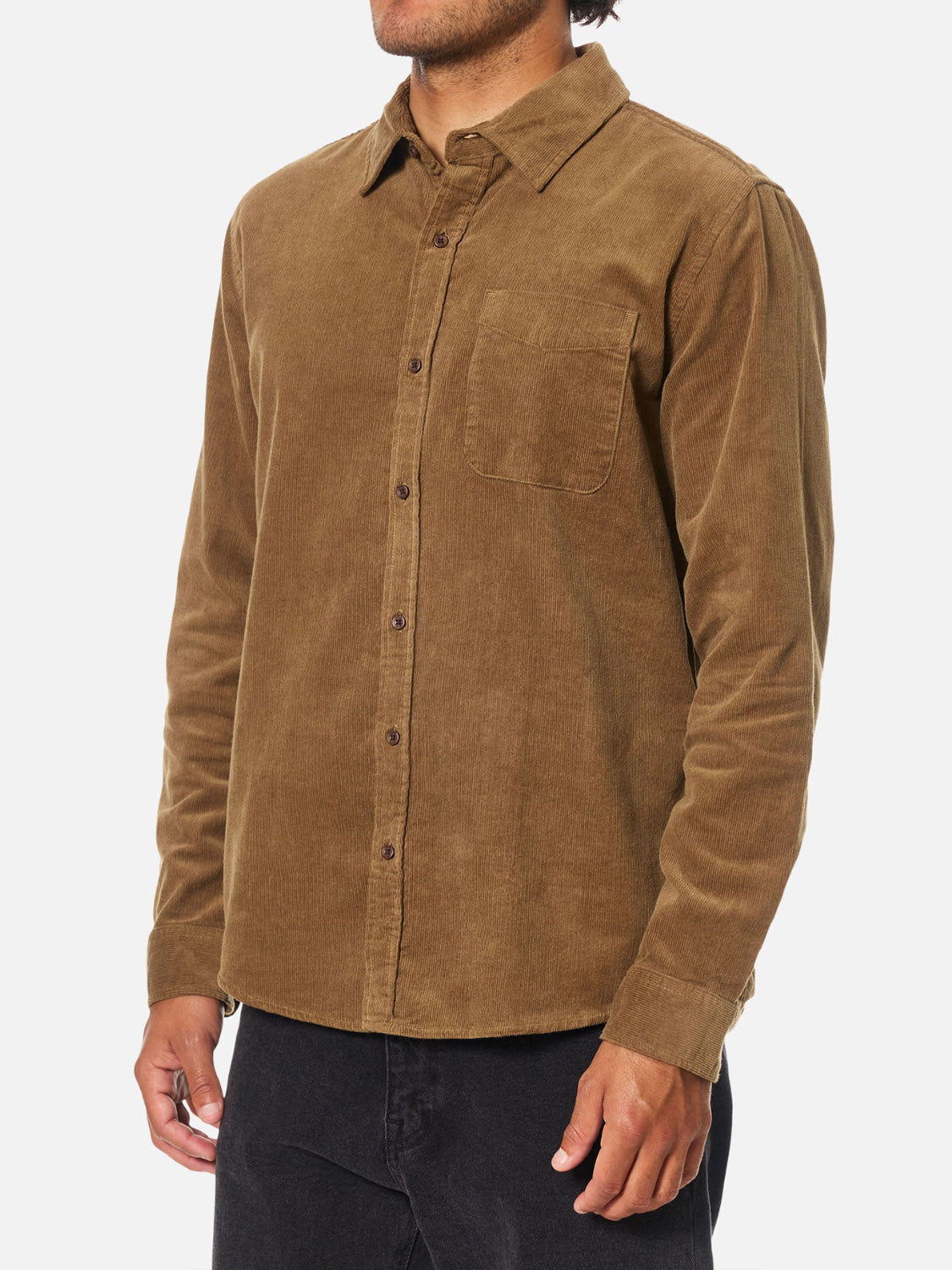 A man wearing the Katin Granada Shirt, a brown cotton corduroy button-down with a chest pocket, and black pants, standing against a plain white background.