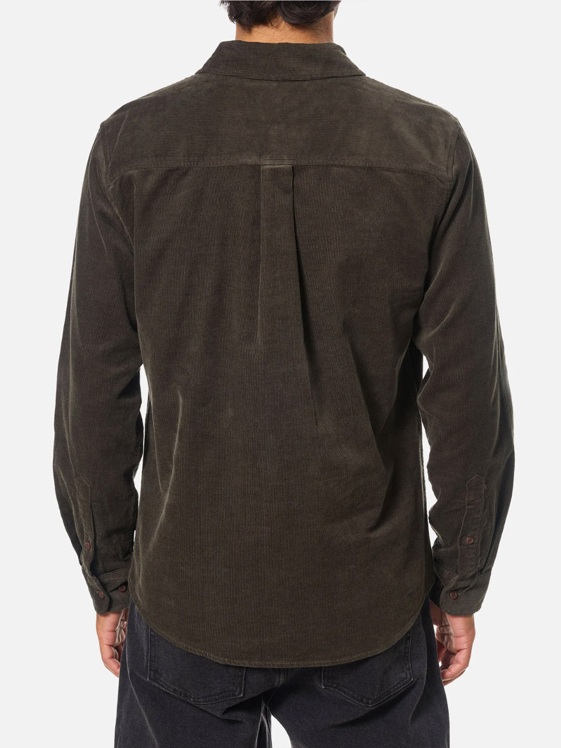 A person is seen from the back wearing the Katin Granada Shirt—a long-sleeve, dark olive green cotton corduroy button-down with a collar, buttoned cuffs, center back box pleat—paired with black pants.