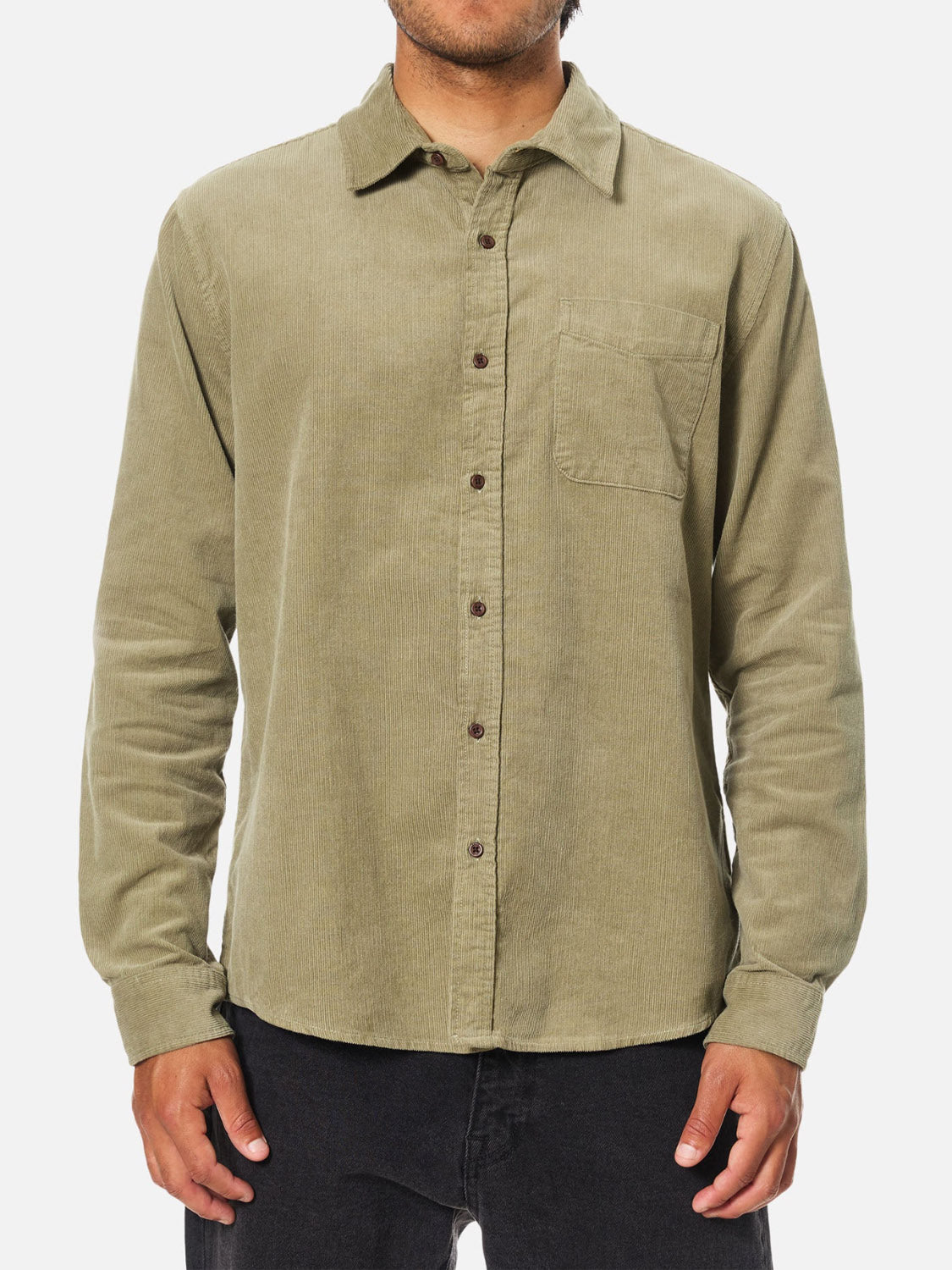 A person wears the Katin Granada Shirt, a men's light olive green corduroy shirt with a chest pocket, paired with black pants. They stand with arms relaxed at their sides against a plain white background.