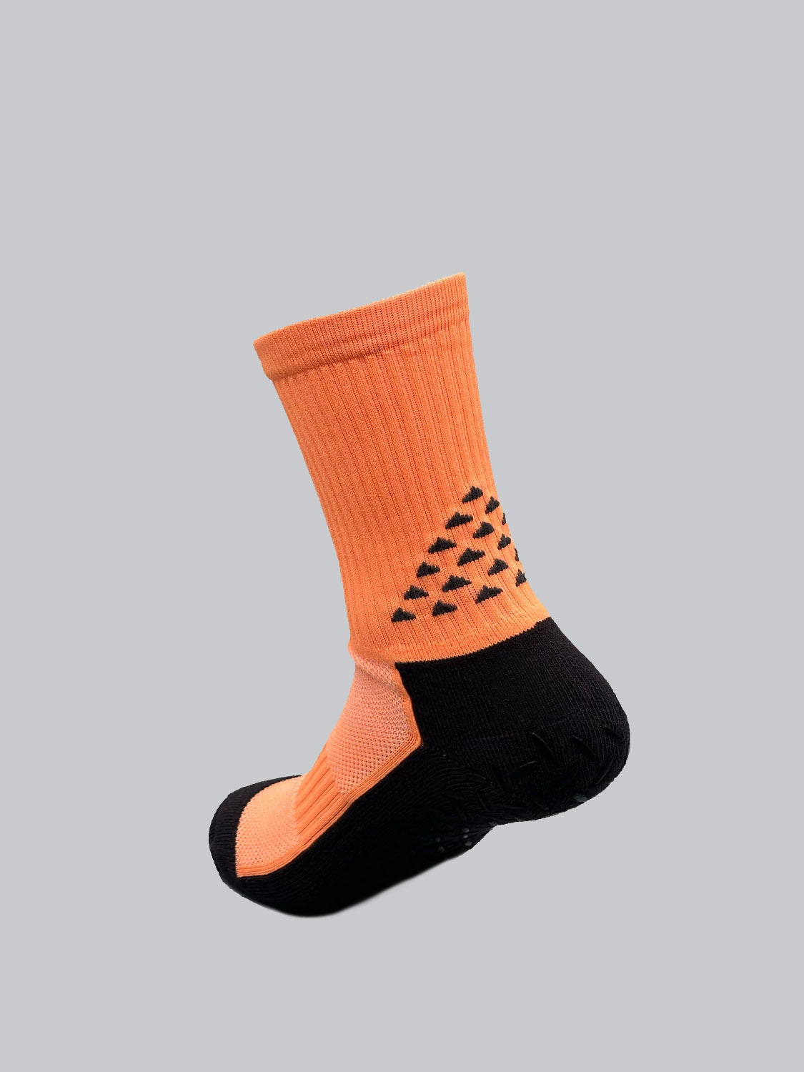 The ID Menswear Grip Sports Socks shown on a gray background are orange with a black triangular design, featuring a textured sole for performance and comfort, and a ribbed upper section for premium grip.
