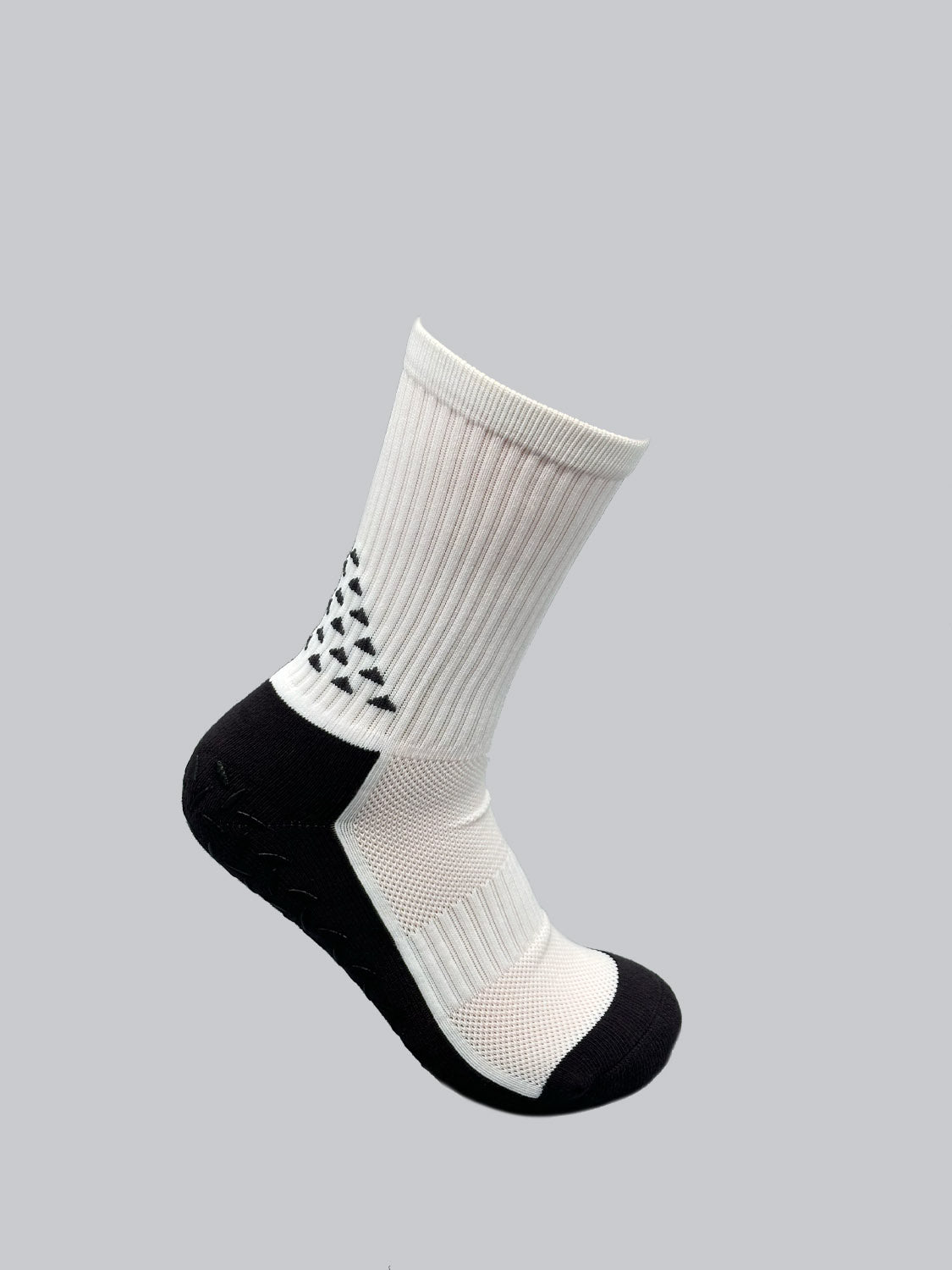 Grip Sports Socks by ID Menswear are stylish white and black socks with a ribbed texture, featuring a geometric black triangle on a gray background. These premium socks offer an anti-slip design to enhance comfort and performance.