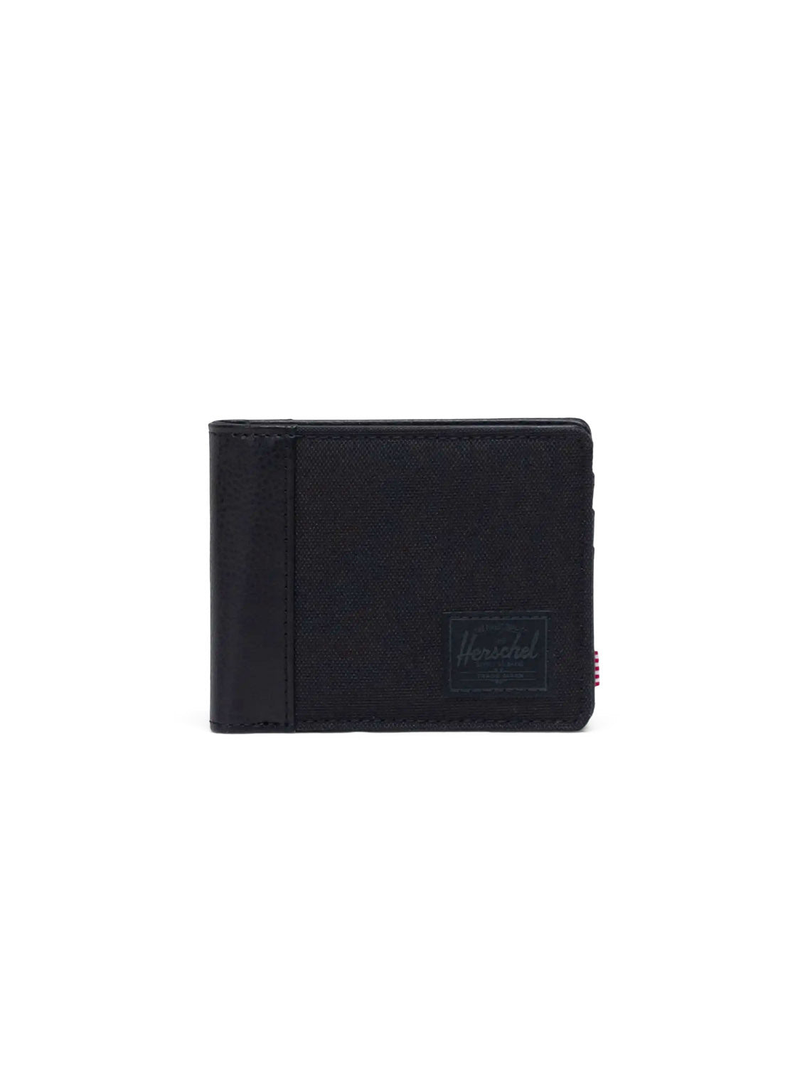 The Herschel Hank Wallet is a black bi-fold made from synthetic leather, featuring a subtle front logo patch. It's shown standing closed against a plain white background.