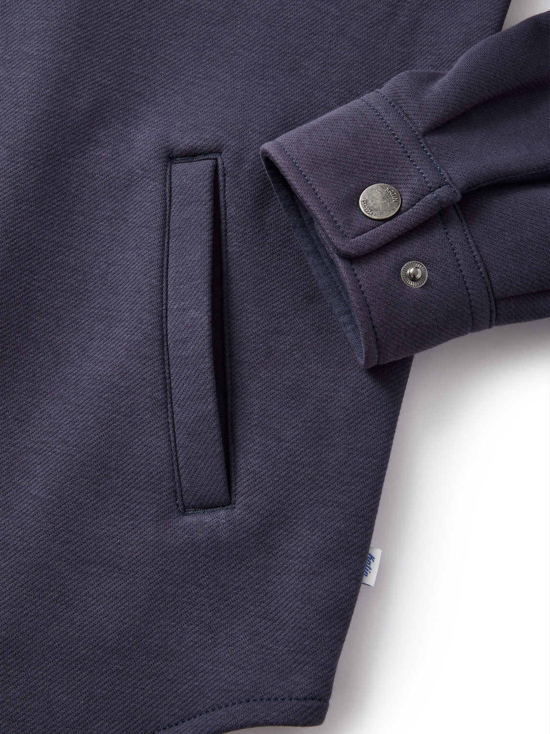 Close-up of a Katin Harold Fleece Jacket sleeve in navy blue, made from a poly-cotton blend. It features a cuff with two metallic snap buttons, a body with a single vertical pocket, and fabric texture showing a subtle woven pattern.