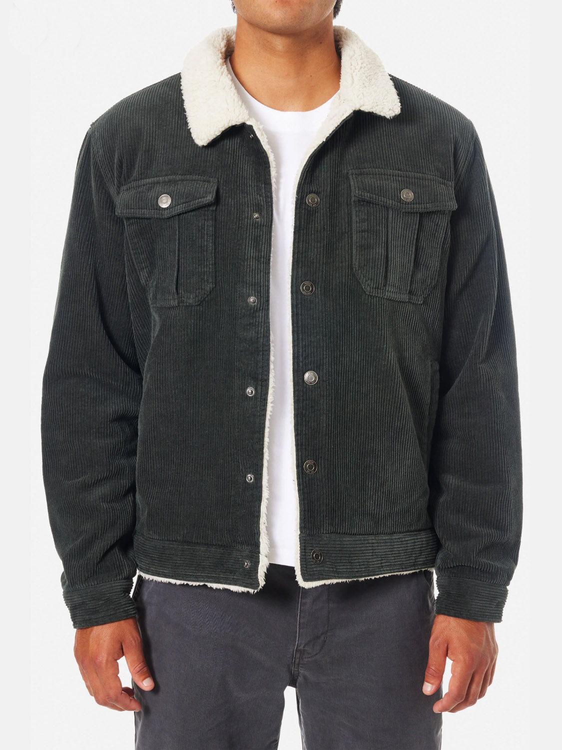 A person wears the Katin Harris Corduroy Jacket in dark green with a white sherpa lining, layered over a white shirt and paired with dark pants, standing against a plain white background.