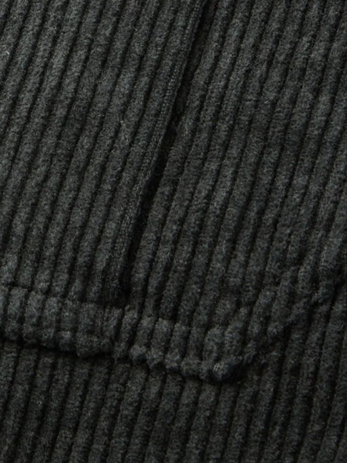 Close-up of the Katin Harris Corduroy Jacket showcases its dark gray corduroy fabric, featuring vertical ridges and a stitched seam along the pocket edge.