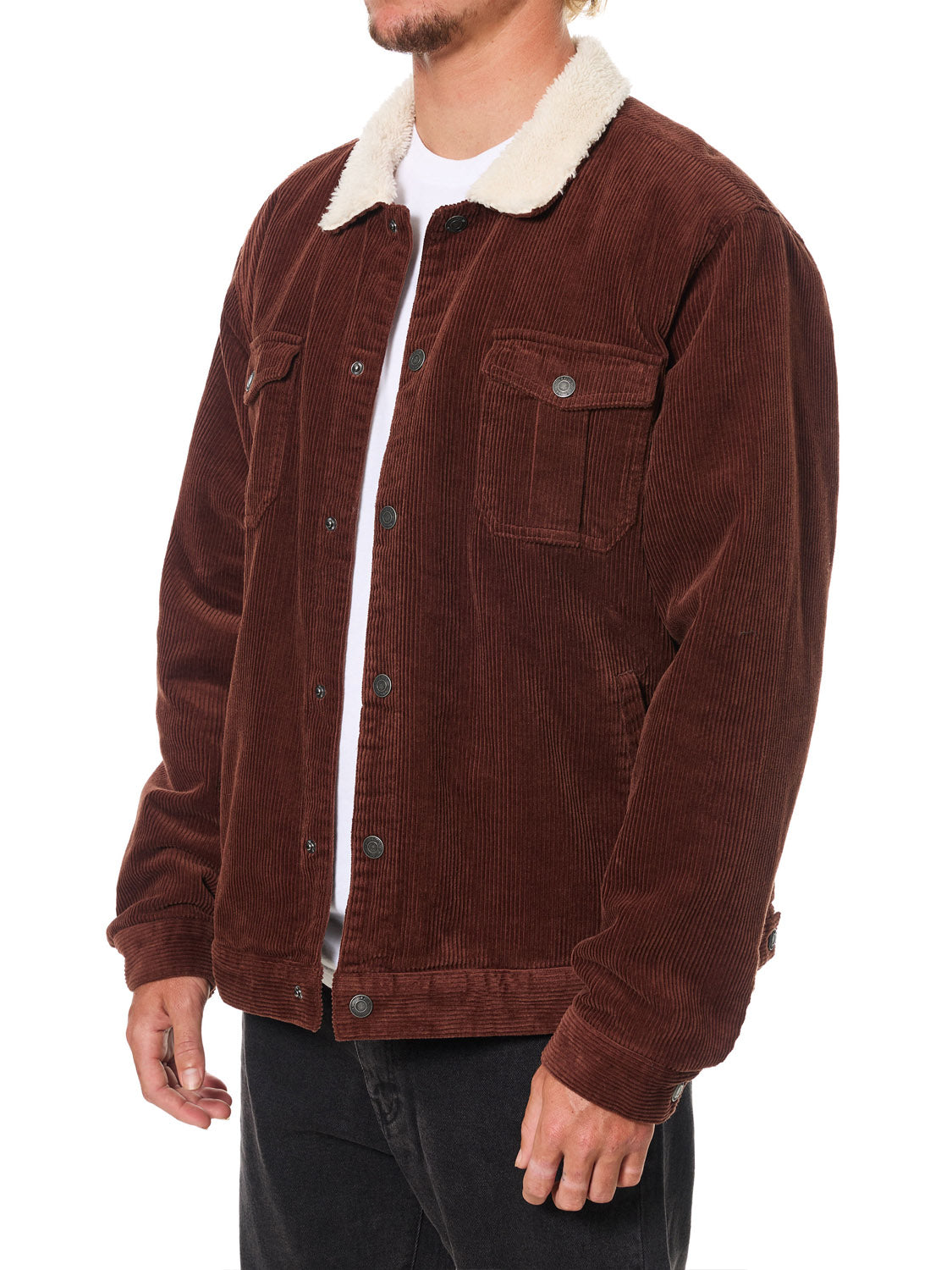 A man wears the Katin Harris Corduroy Jacket, a brown jacket with a white sherpa collar, over a white shirt. The sherpa-lined jacket has buttoned chest pockets and side pockets, shown against a plain white background.