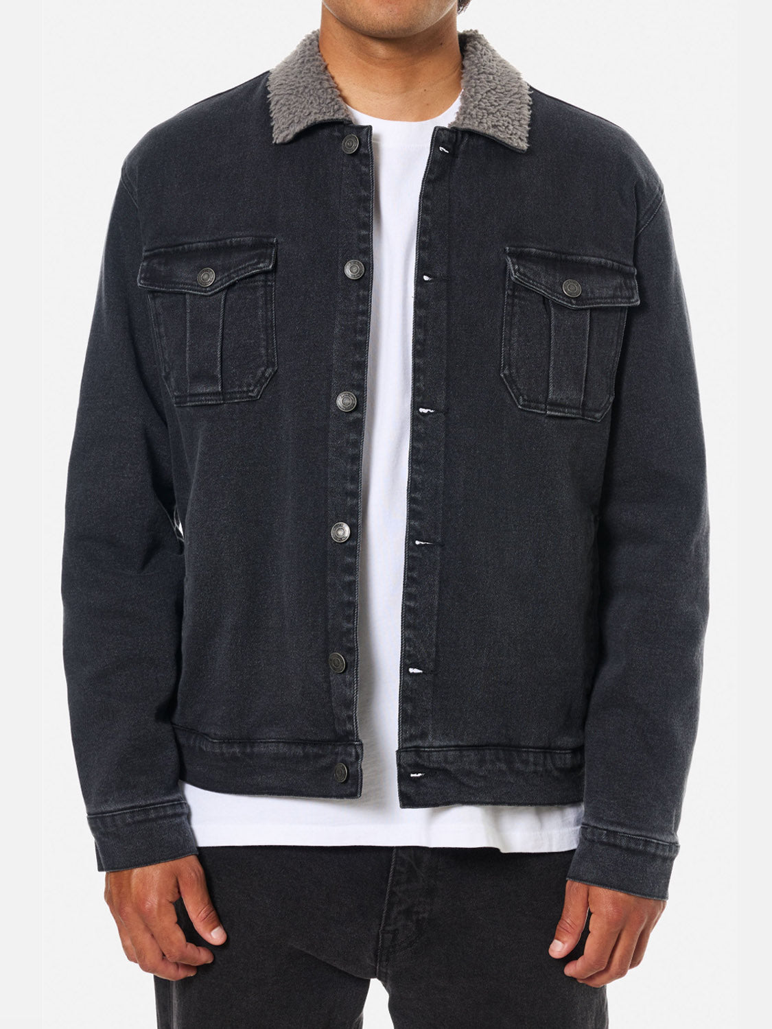 A man wears the Katin Harris Denim Jacket—black with chest patch pockets and a gray sherpa collar—over a white t-shirt and black pants, standing against a plain white background.