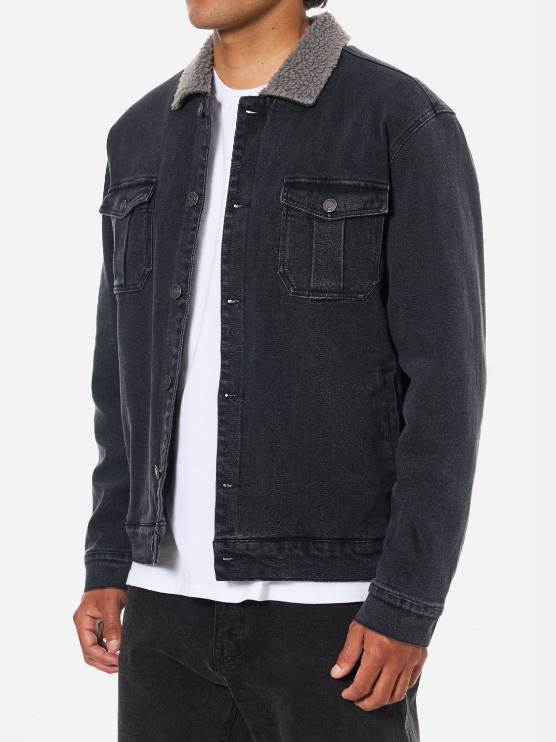 A person wearing the Katin Harris Denim Jacket—black denim with chest patch pockets and a gray sherpa collar—over a white t-shirt and black pants, shown waist up against a plain background.