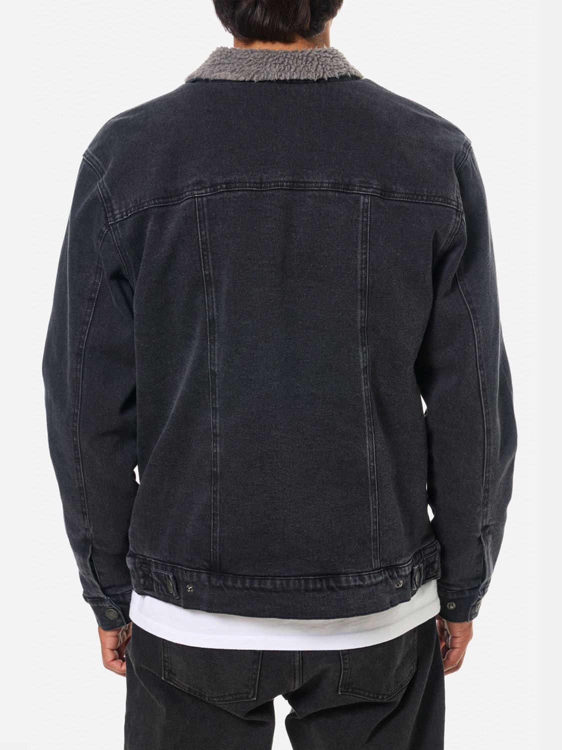 A person is shown from the back wearing the Katin Harris Denim Jacket in black with a gray sherpa collar and chest patch pockets, layered over a white shirt and paired with black pants.
