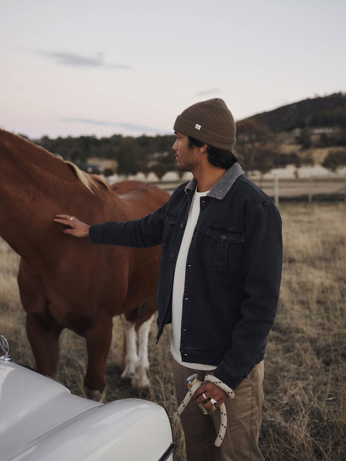 A man in the Katin Harris Denim Jacket, featuring chest patch pockets and a warm sherpa collar, gently touches a horse.