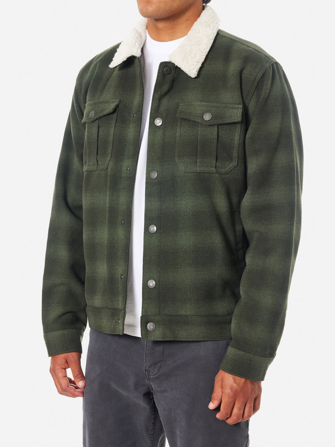 Someone is wearing a Katin Harris Plaid Jacket in green, featuring a white sherpa collar and buttoned front pockets. This wool plaid jacket is complemented by a white shirt and dark pants, highlighting the clothing rather than the individual.