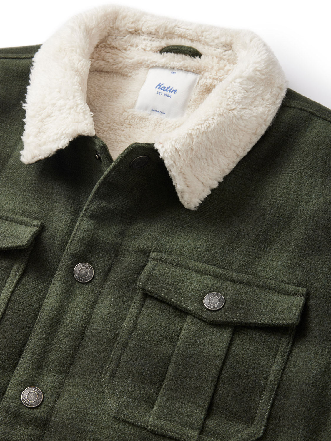 The Katin Harris Plaid Jacket highlights a green wool plaid design, two chest pockets, and snap buttons. Its distinctive feature is the soft white sherpa liner collar. The tag inside the collar is visible but unreadable.