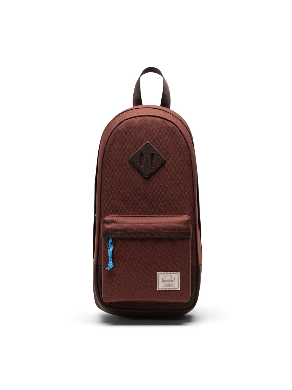 The Herschel Heritage Shoulder Bag - 8L is a brown bag made from recycled polyester with a front zip pocket featuring a blue pull, a top handle, and a rectangular white brand label. It's shown against a plain white background.