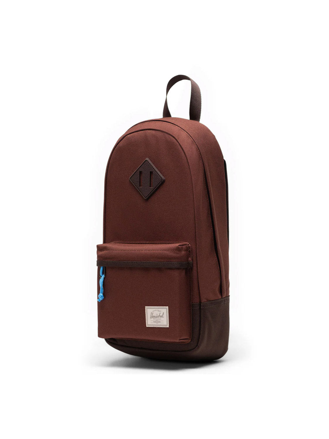 The Herschel Heritage Shoulder Bag - 8L, crafted from recycled polyester in brown, features a front zip pocket, white label, blue zipper pull, top handle, and diamond patch. Displayed against a plain white background.