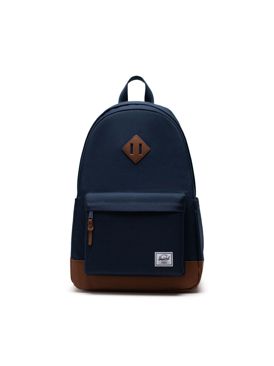 The Herschel Heritage Backpack in navy blue features brown leather accents, a front zip pocket, side pockets, top handle, and a diamond patch, shown against a white background.